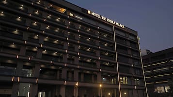 A multi-story hotel building with illuminated signage for "Hotel The Indra Palace."
