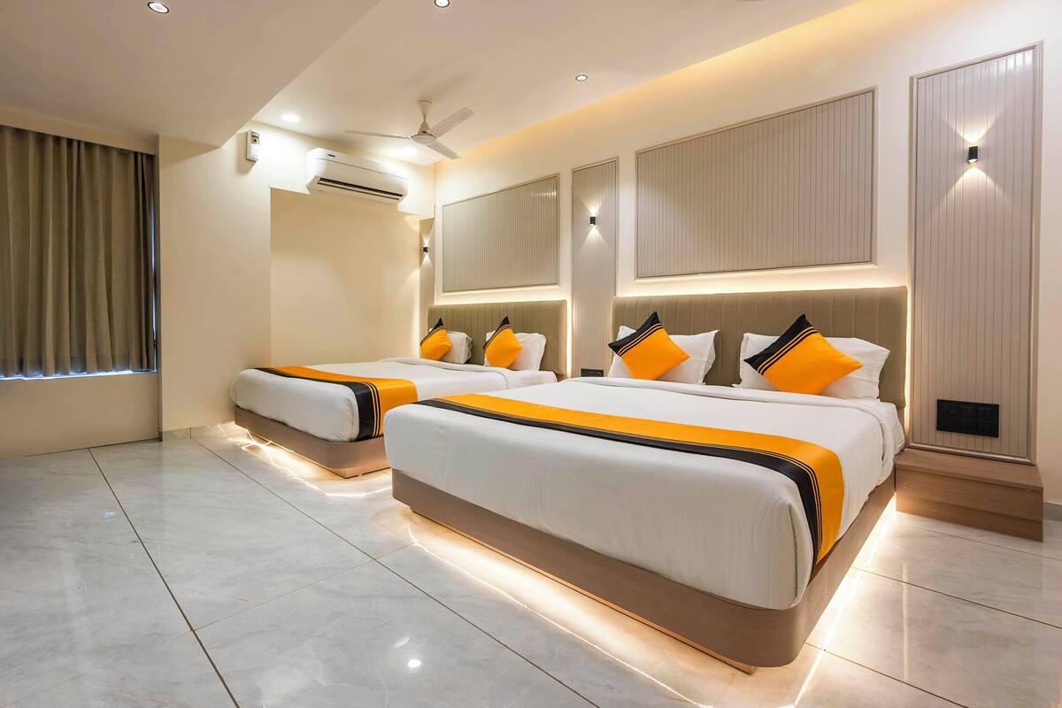 Una habitación de hotel moderna con dos camas, un ventilador de techo, un equipo de aire acondicionado y un ventanal con cortinas.