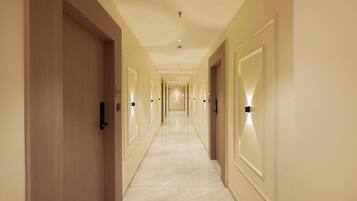 A long, narrow hotel corridor with wooden doors on one side and light-colored walls on the other.