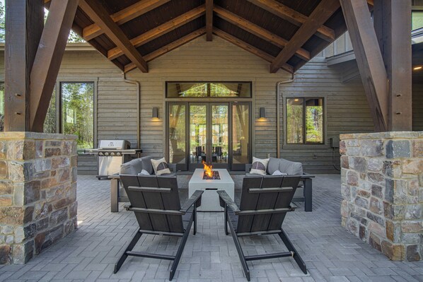 An outdoor patio with stone walls, a fire pit, and a grill.