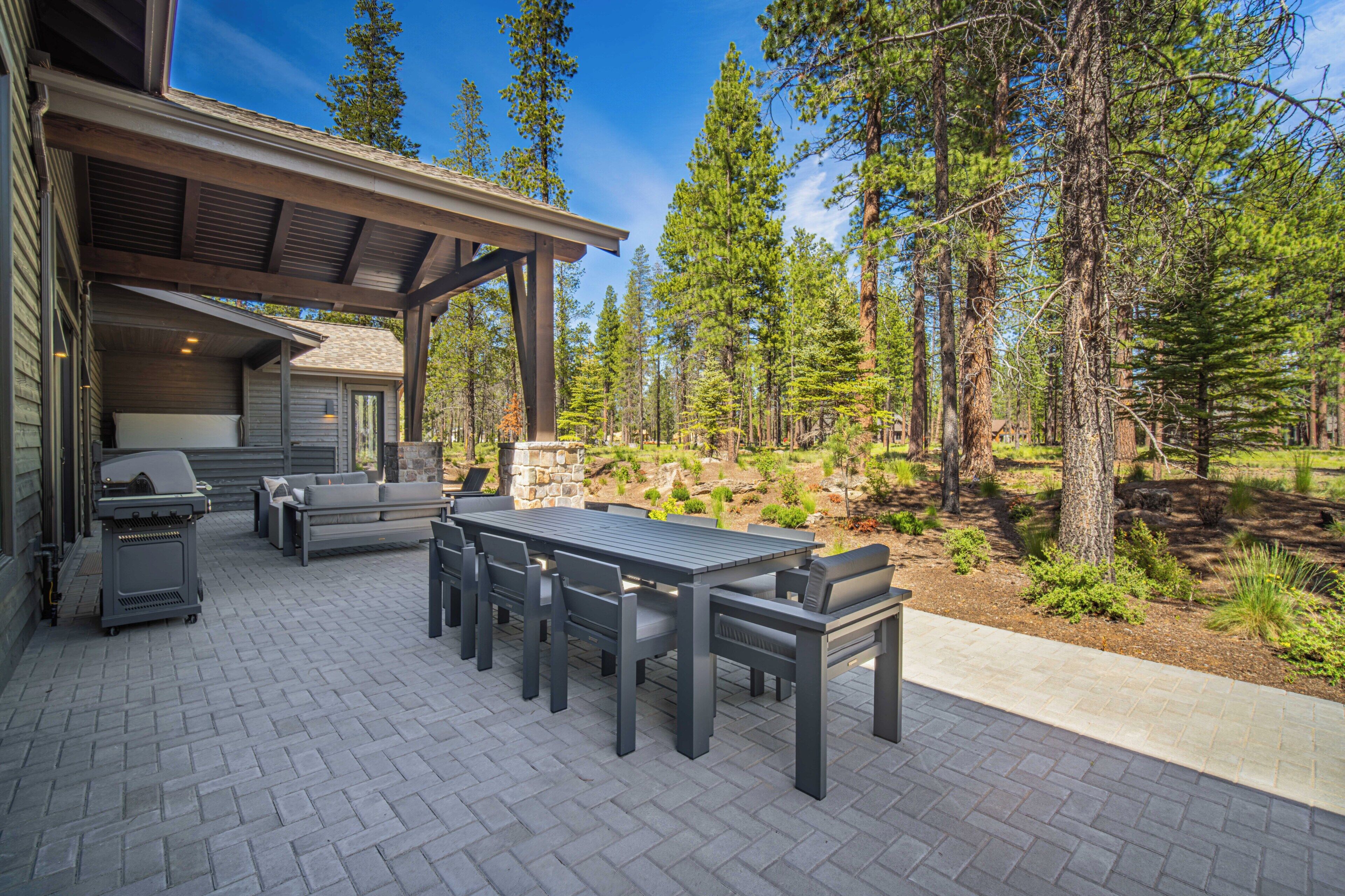 Eine Terrasse im Freien mit Grill, Sitzgelegenheit und Blick auf einen Wald.