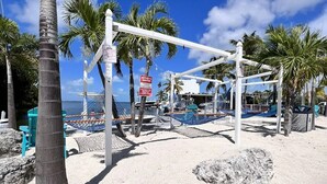 A beach volleyball court with a net, palm trees, and a sign warning of renters. - Cozy campground in tranquil Key Largo (Key Largo)