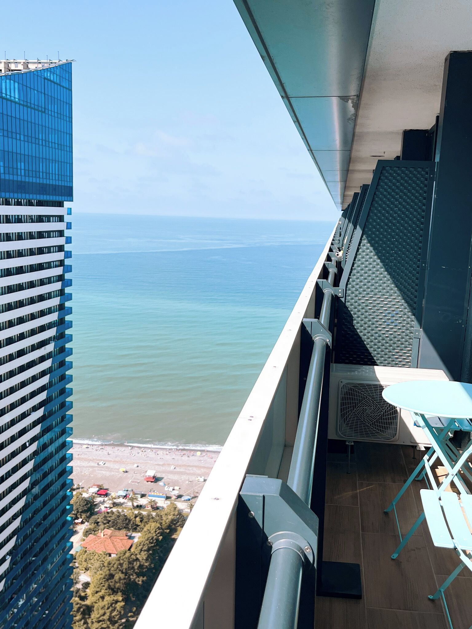 Ein Balkon mit Blick auf das Meer und ein Hochhaus.