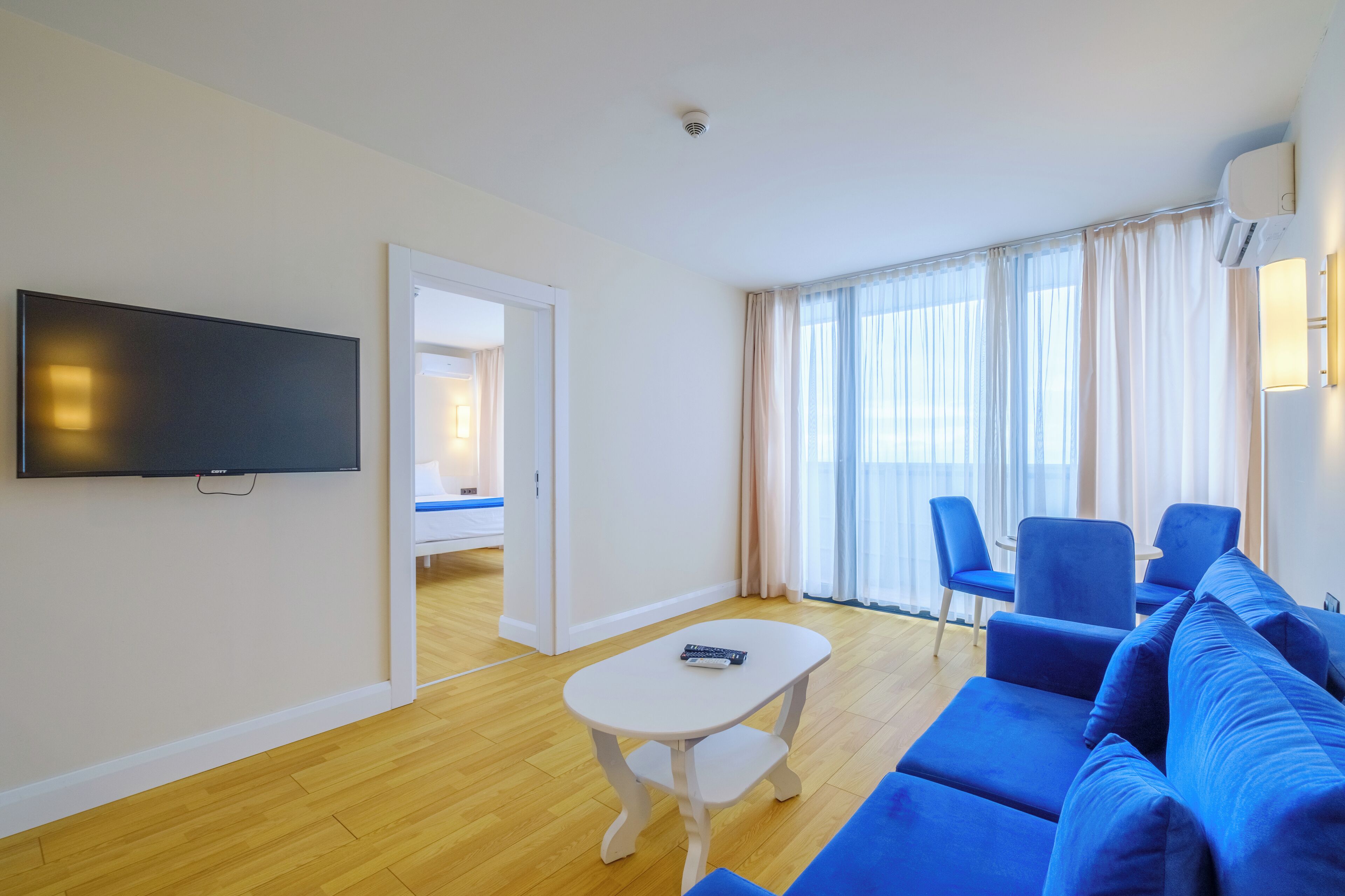 Ein modernes Wohnzimmer mit einem blauen Sofa, einem weißen Couchtisch und einem flachbildfernseher an der Wand.