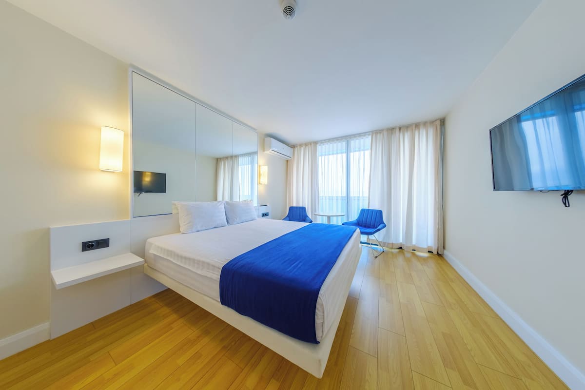 Een moderne hotelkamer met een groot bed, een televisie, een bureau en een stoel.