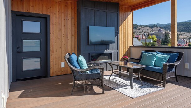 A covered outdoor area with a fireplace, seating, and a TV screen.