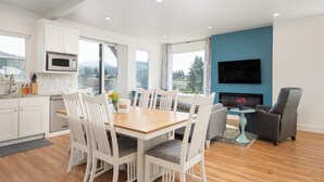 A modern kitchen with white cabinets, a microwave, and a dining area with a wooden table and white chairs.
