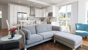 A modern living room with a grey sectional sofa, a small round table with a vase of flowers, and a blue armchair.