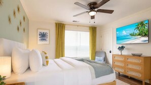 A bedroom with a bed, a ceiling fan, a TV, a window with curtains, and a wooden dresser. - Walk to Stadium | Hot Tub • Fire Pit • Parking (Atlanta)