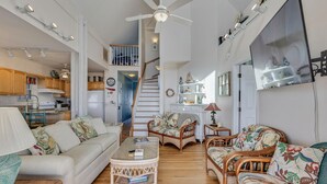 A spacious living area with a white sofa, wicker chairs, a coffee table, and a staircase leading to an upper level. - Legasea - Ocean Front home with direct Beach Access, Large Decks, great for larg (Carolina Beach)