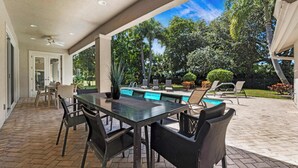 An outdoor patio with a pool, dining area, and garden view. - Palm House GolfCourseViews Pool 5bd/5bth&Game Room (Naples)
