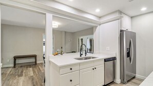 A modern kitchen with white cabinetry, a stainless steel refrigerator, and a built-in dishwasher. - Pet Friendly Sea Pines Retreat (Hilton Head Island)