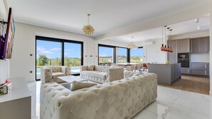 Un salon moderne avec un grand canapé, un coin repas et une cuisine dotée de meubles gris.