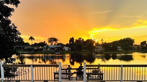 A wooden deck with a pool, overlooking a calm lake at sunset. - Lakefront Pool Family Home in Hollywood 10 minutes to HardRock stadium  (Pembroke Pines)