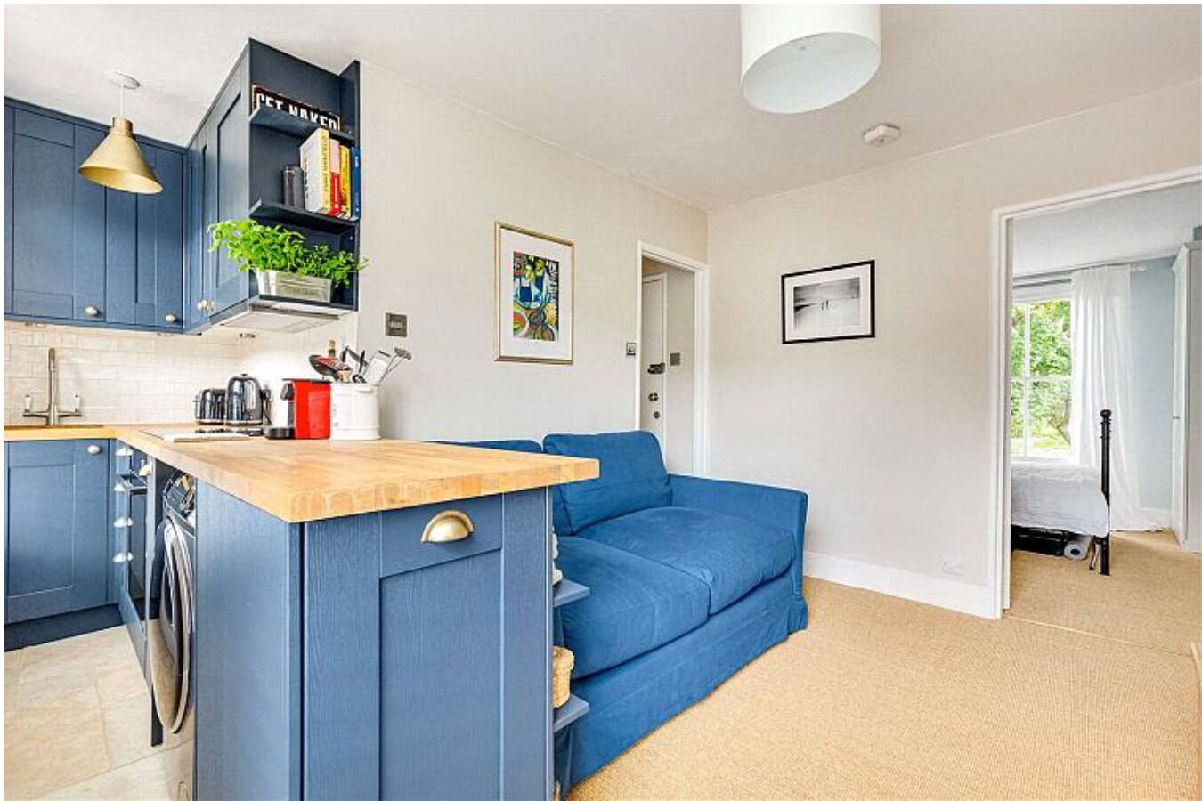 A compact living space with a kitchenette, a blue sofa, and a dining area.