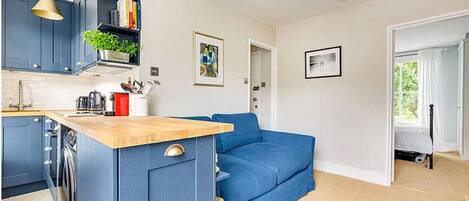 A compact living space with a kitchenette, a blue sofa, and a dining area.
