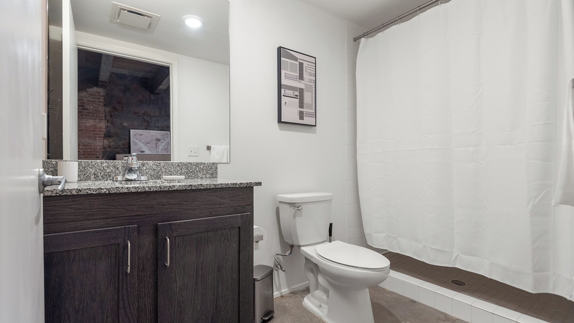 Un baño con inodoro, lavamanos y cortina de ducha.