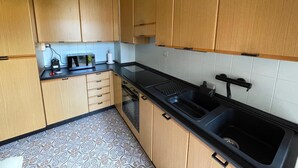 A kitchen with wooden cabinets, a black countertop, a sink, and a patterned floor. - DA VINCI Residence - Between the Racetrack and the Historic Center (Imola)