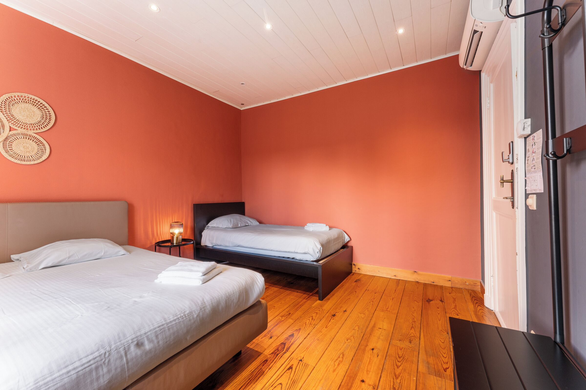 Ein Schlafzimmer mit zwei Betten, Holzboden und Deckenventilator.