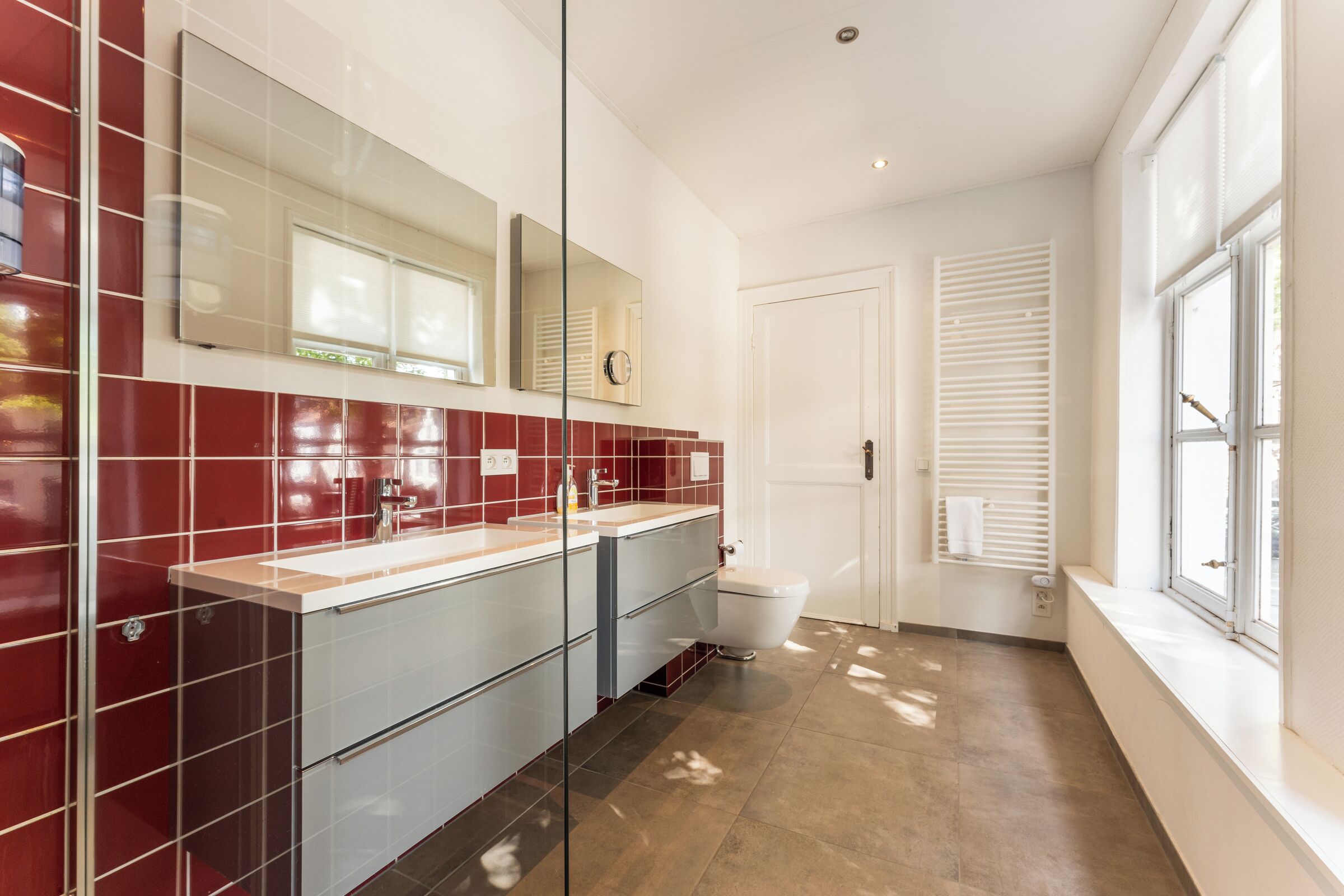 A modern bathroom with a glass shower enclosure, a white toilet, and a vanity with a mirror.