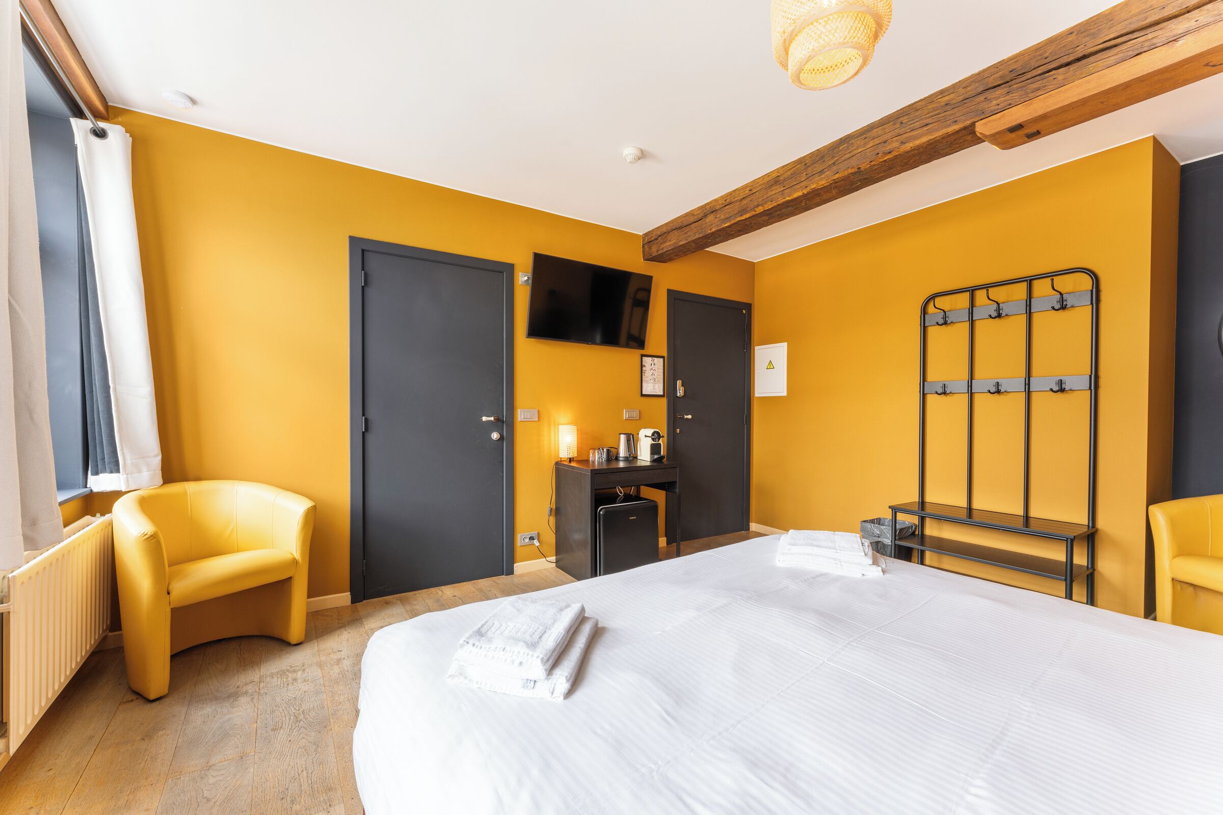 A hotel room with a large bed, a desk, a chair, and a TV.