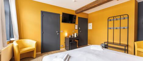 A hotel room with a large bed, a desk, a chair, and a TV.