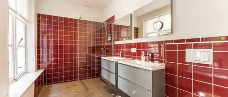 Un baño moderno con azulejos rojos, un lavabo blanco y un espejo grande.