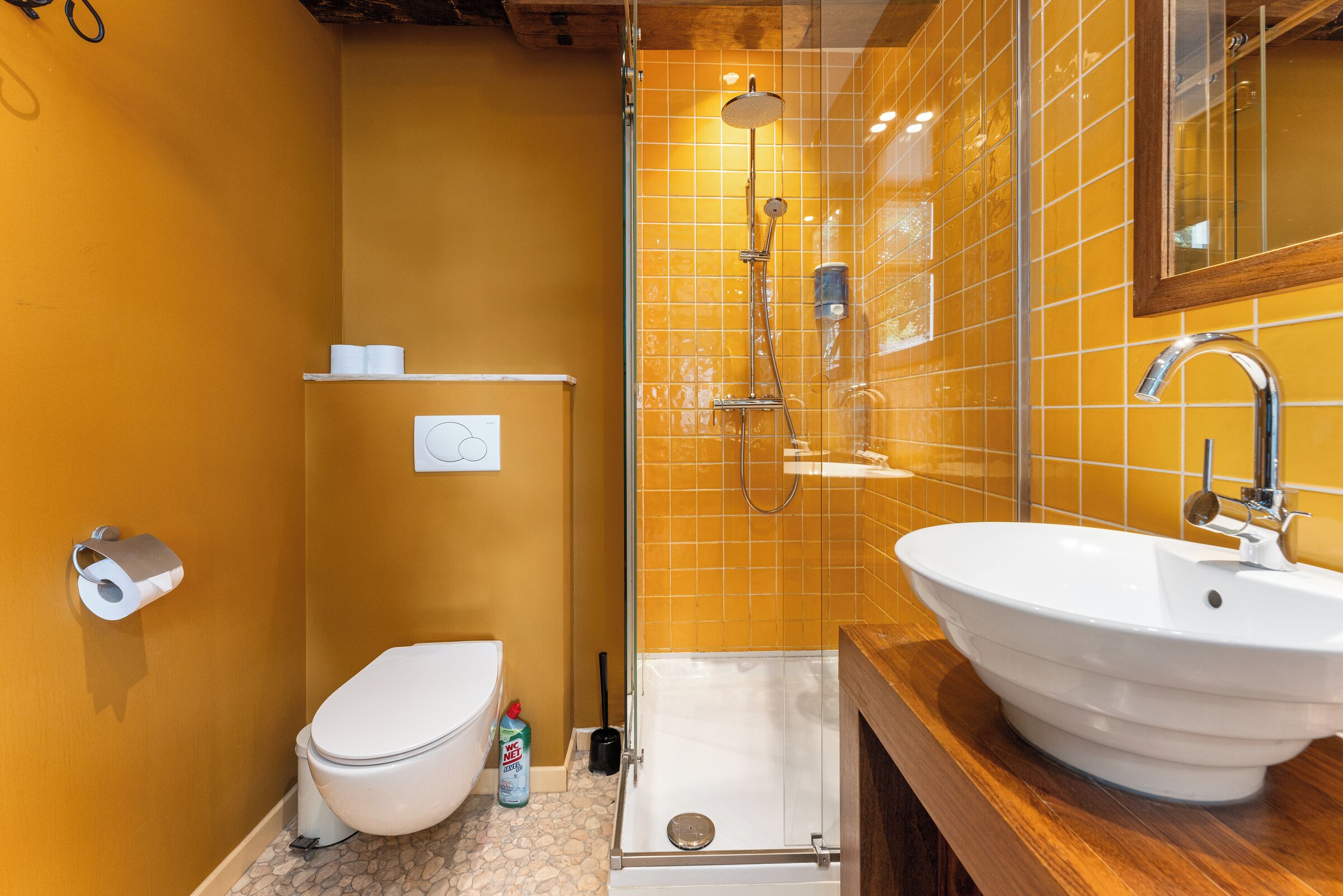 A bathroom with a white toilet, a shower with a glass door, and a sink with a wooden countertop.