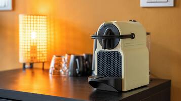 A vintage espresso machine on a wooden counter with a textured lamp in the background.