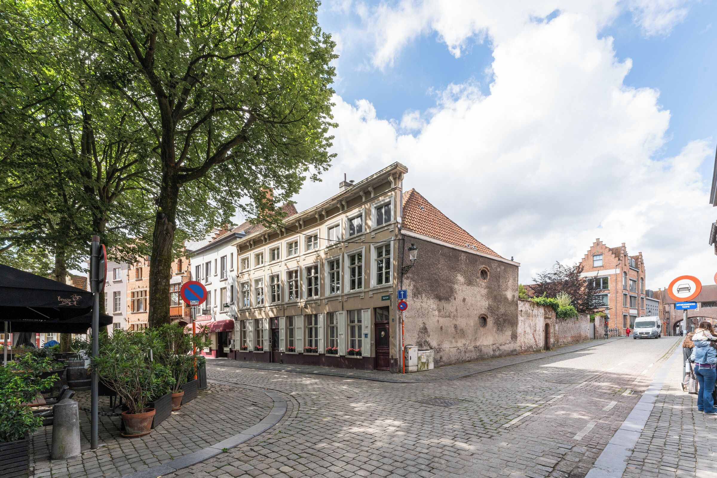 En historisk bygning med tegltag, store vinduer og en brostensbelagt gade.