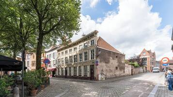 En historisk bygning med tegltag, store vinduer og en brostensbelagt gade.