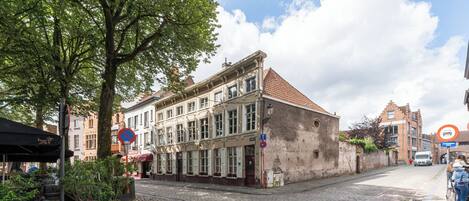 Un edificio histórico con tejado de tejas, ventanas amplias y una calle empedrada.