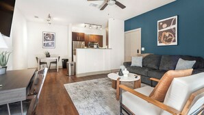 Ein modernes Wohnzimmer mit grauem Sofa, Couchtisch und Essbereich mit Tisch und Stühlen.
