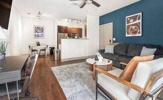A modern living room with a grey sofa, a coffee table, and a dining area with a table and chairs.
