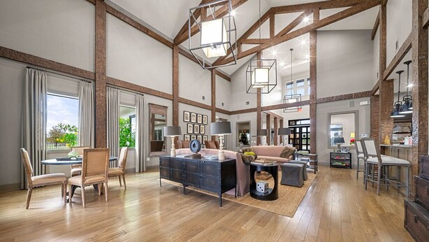 Ein geräumiges Wohnzimmer mit Holzböden, einer zentralen Sitzecke und einer Küche im Hintergrund.