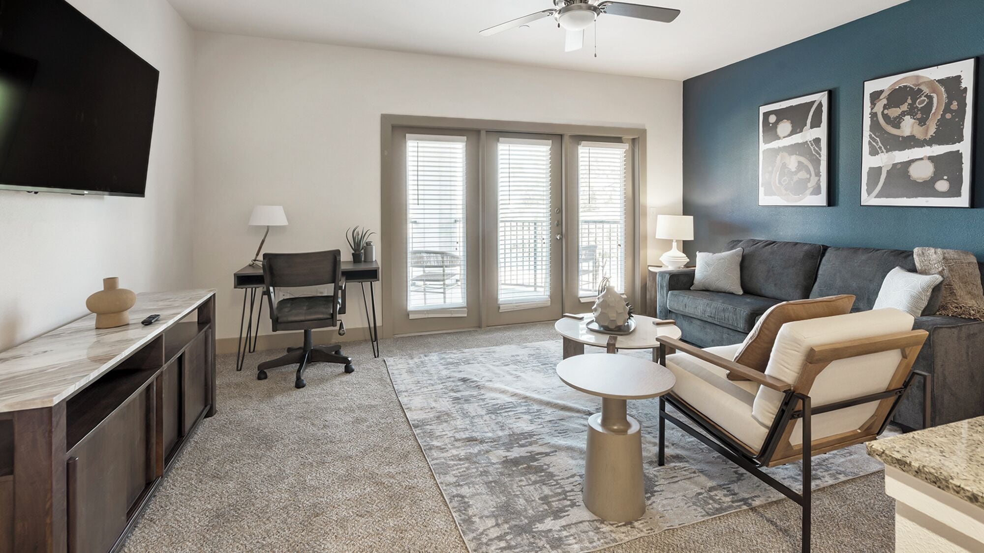 A modern living room with a flat-screen TV, a desk, a chair, a sofa, and a coffee table.