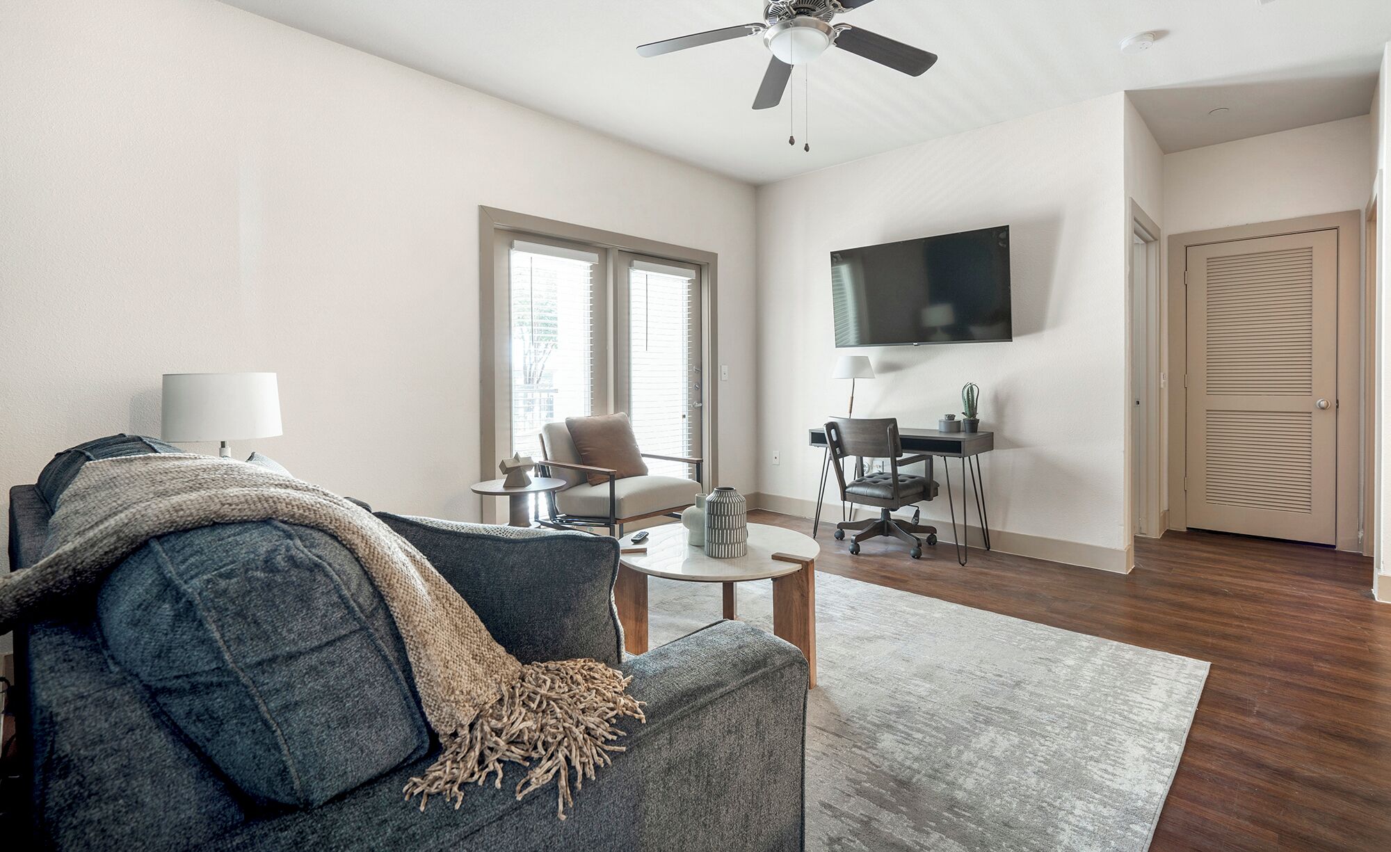 A modern living room with a sofa, coffee table, and a TV mounted on the wall.