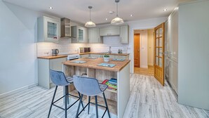 A modern kitchen with a central island, bar stools, and pendant lighting. - One Bed in Guilden Sutton by Guestz (Guilden Sutton)