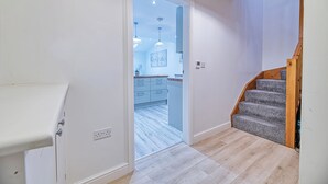 A modern kitchen with white cabinets, a wooden staircase, and a light-colored floor. - One Bed in Guilden Sutton by Guestz (Guilden Sutton)