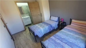A bedroom with two beds, a wardrobe, and a small bedside table with a lamp. - Hello Roma 2 (Rome)