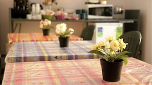 A dining area with tables covered in plaid tablecloths, potted plants, and a microwave in the background. - Hello Roma 2 (Rome)