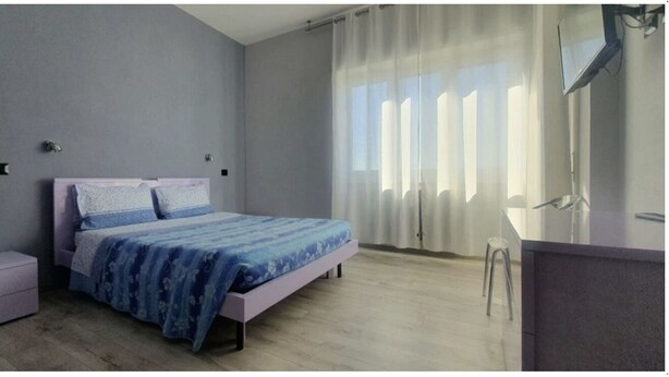 A bedroom with a bed, a nightstand, a dresser, and a window with curtains. - Hello Roma 2 (Rome)