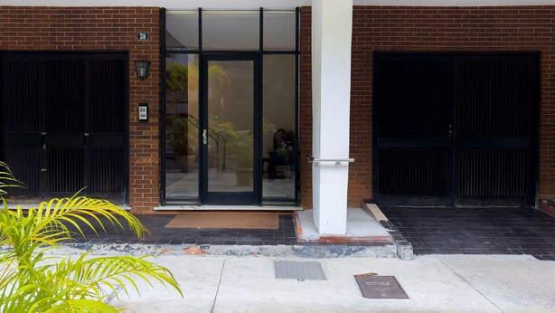 Un edificio con fachada de ladrillo, número 59, que presenta una entrada con puerta de vidrio y dos puertas negras.