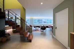 A modern interior with a staircase, a dining area, and a large window.