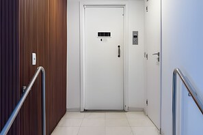 A hallway with a white door, a handrail, and a wall with vertical lines. - Ipanema | Duplex no melhor local do bairro, 4 quartos, 5 min da Praia - por Casapē Rio (Rio de Janeiro)