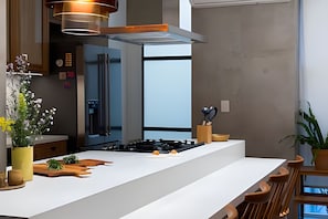 A modern kitchen with a central island, a built-in stove, and a water dispenser. - Ipanema | Duplex no melhor local do bairro, 4 quartos, 5 min da Praia - por Casapē Rio (Rio de Janeiro)