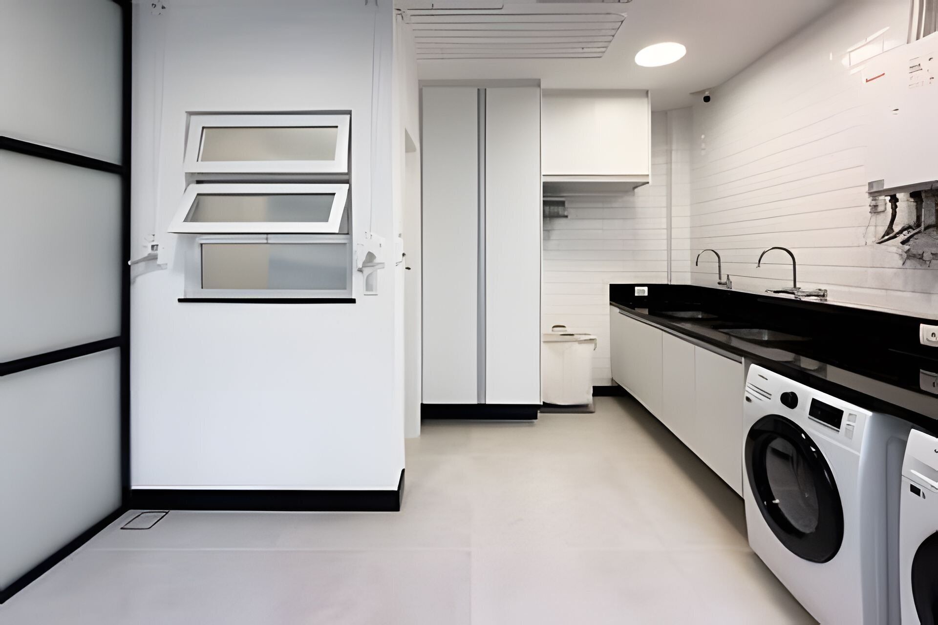 A modern kitchen with a washing machine, a sink, and a door with a window.