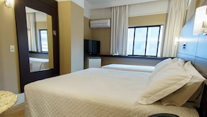 A hotel room with a large bed, a bedside telephone, an air conditioning unit, a television, and a window with curtains. - Modern Triplo Casal Stay with Sleek Design Close to São Paulo Attractions (São Paulo)