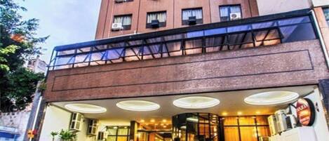 A hotel with a modern design, featuring a brick facade, a glass entrance, and a staircase leading to the lobby.