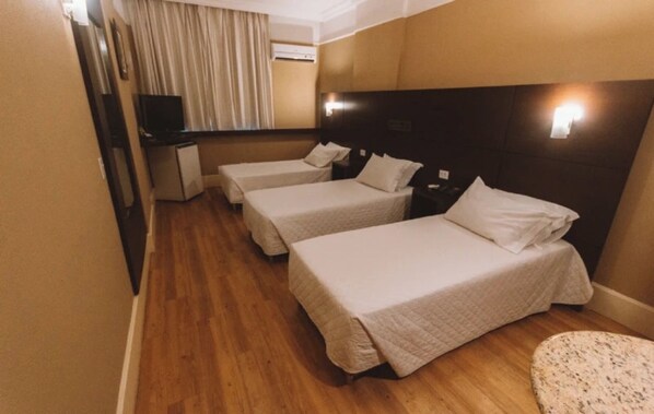 A hotel room with three single beds, a small desk with a computer, and a television. - Central SP Adventure Hub – Triplo Twin w/ Pet Option & Business-Friendly Setup (São Paulo)